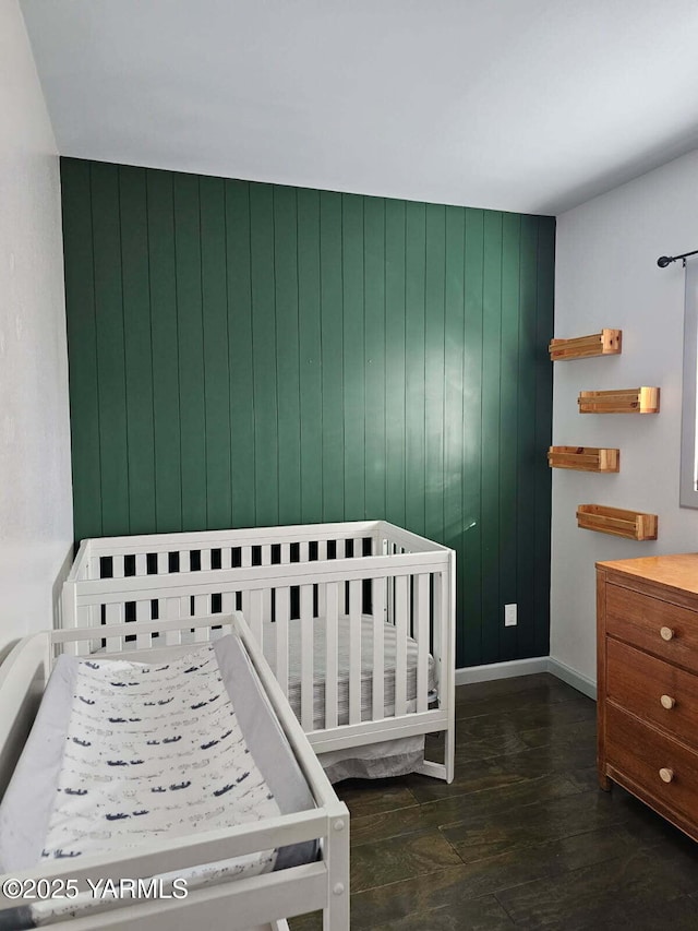 bedroom with wood walls, wood finished floors, and baseboards