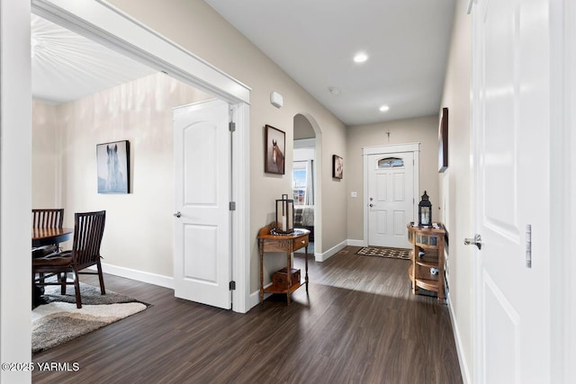 entrance foyer featuring arched walkways, recessed lighting, dark wood-style floors, and baseboards