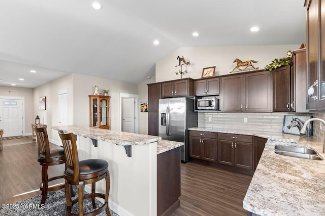 kitchen featuring dark wood finished floors, a breakfast bar area, stainless steel appliances, a sink, and dark brown cabinets