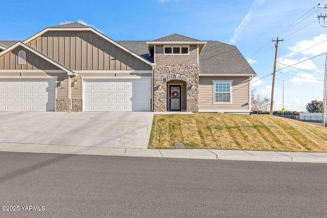 view of front of property with a garage, concrete driveway, stone siding, a front lawn, and board and batten siding