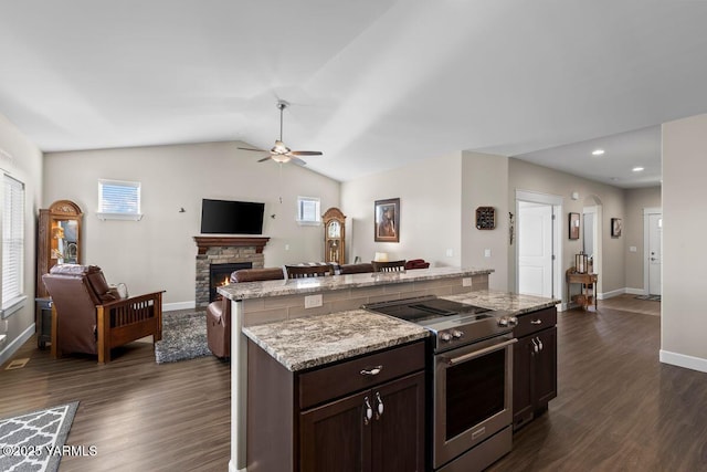 kitchen with stainless steel electric stove, lofted ceiling, dark wood-type flooring, a kitchen island, and a stone fireplace