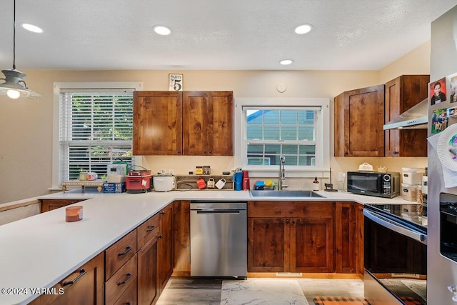 kitchen with appliances with stainless steel finishes, decorative light fixtures, light countertops, a sink, and recessed lighting