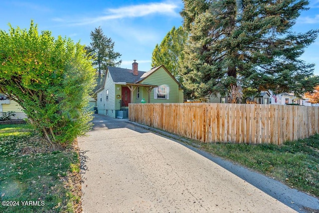 bungalow with a fenced front yard, driveway, and a chimney