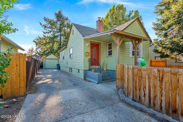 view of front of home with an outbuilding, a chimney, concrete driveway, fence, and a garage