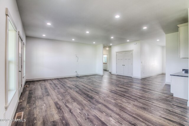 unfurnished living room featuring recessed lighting, baseboards, and dark wood-style floors