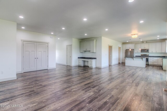 unfurnished living room with dark wood finished floors, recessed lighting, and baseboards