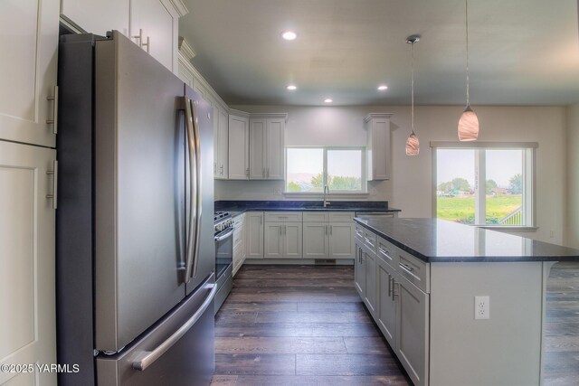 kitchen featuring a kitchen island, recessed lighting, a sink, stainless steel appliances, and dark wood-type flooring