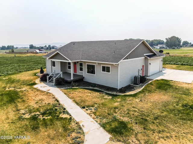 view of front of home with a front yard, driveway, roof with shingles, an attached garage, and board and batten siding