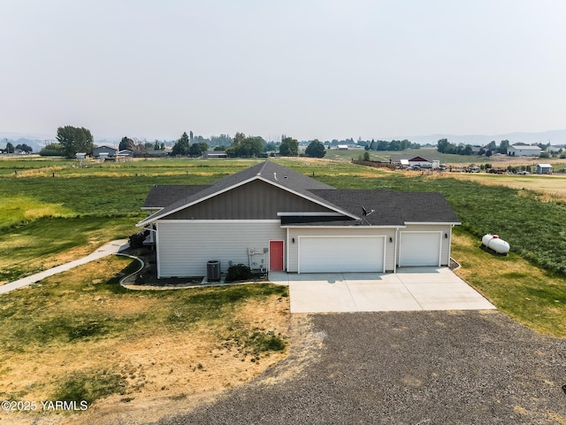 view of front of home featuring a garage, central air condition unit, concrete driveway, and a front yard