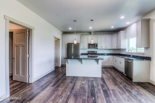 kitchen with a sink, stainless steel appliances, a breakfast bar, and dark wood-style floors