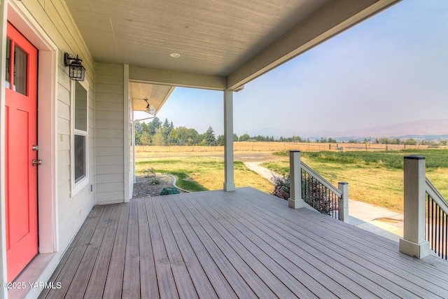 wooden terrace featuring a yard, a rural view, and fence