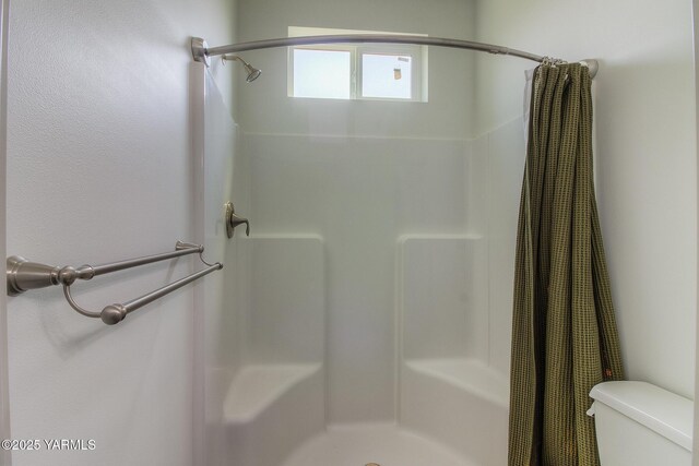 full bath with toilet and a stall shower