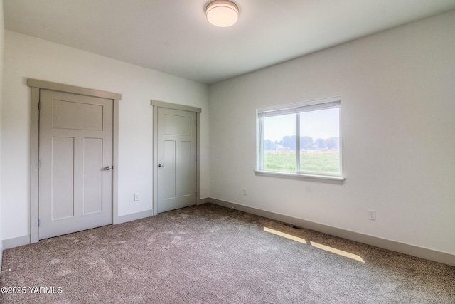 unfurnished bedroom with carpet flooring, visible vents, and baseboards