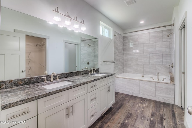 bathroom with double vanity, visible vents, wood finished floors, and a sink