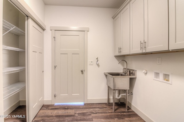 washroom featuring dark wood-style floors, baseboards, cabinet space, a sink, and washer hookup