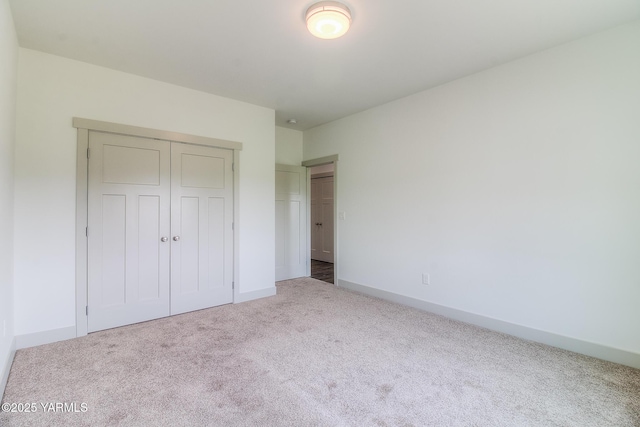 unfurnished bedroom featuring a closet, baseboards, and carpet flooring