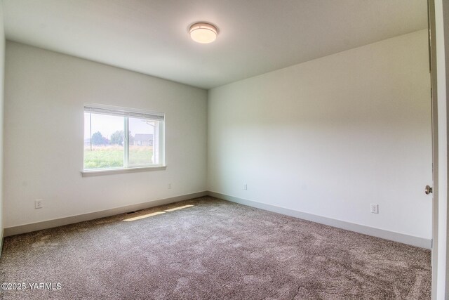 carpeted spare room featuring baseboards