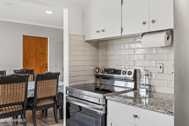 kitchen featuring light stone counters, wood finished floors, ornamental molding, decorative backsplash, and stainless steel range with electric cooktop
