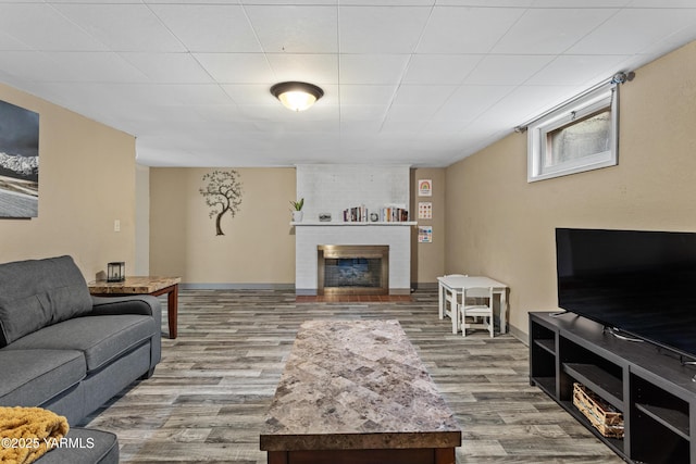 living area featuring a fireplace, baseboards, and wood finished floors