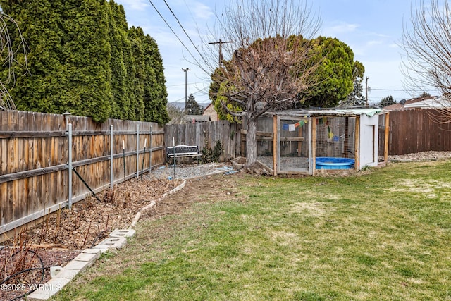 view of yard featuring an outbuilding, a fenced backyard, and exterior structure