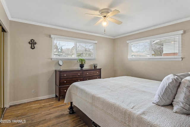 bedroom featuring a ceiling fan, wood finished floors, baseboards, a closet, and crown molding