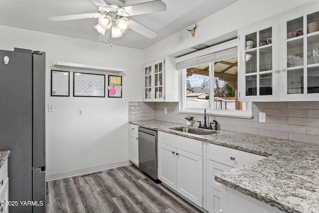 kitchen with decorative backsplash, wood finished floors, white cabinets, stainless steel appliances, and a sink