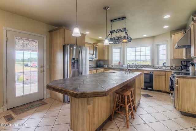 kitchen featuring appliances with stainless steel finishes, pendant lighting, a kitchen island, and a kitchen bar