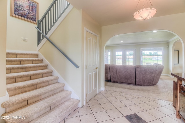 stairs featuring arched walkways, tile patterned flooring, and crown molding