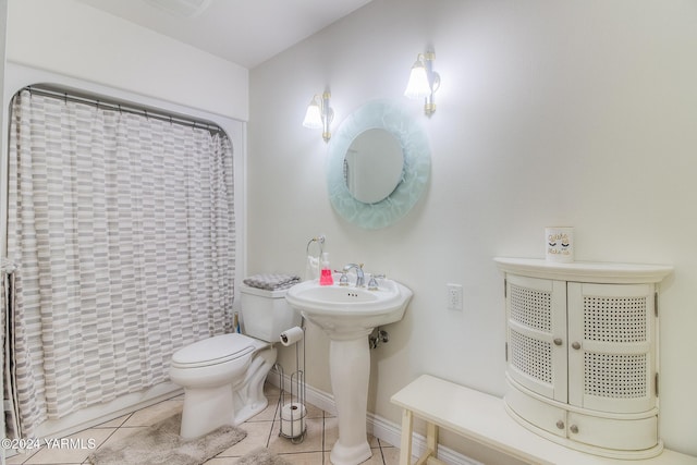 bathroom with toilet, a shower with shower curtain, a sink, baseboards, and tile patterned floors