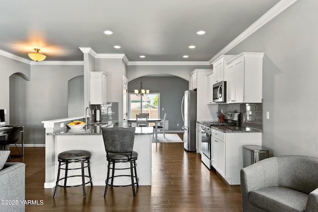7402 Viewcrest Way, Yakima, WA 98908 - kitchen with stainless steel appliances, arched walkways, open floor plan, white cabinets, and crown molding