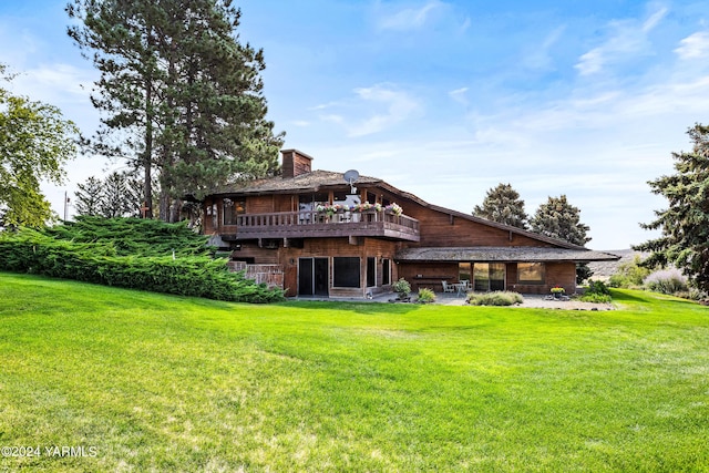 back of property featuring a wooden deck, a chimney, a lawn, and a patio