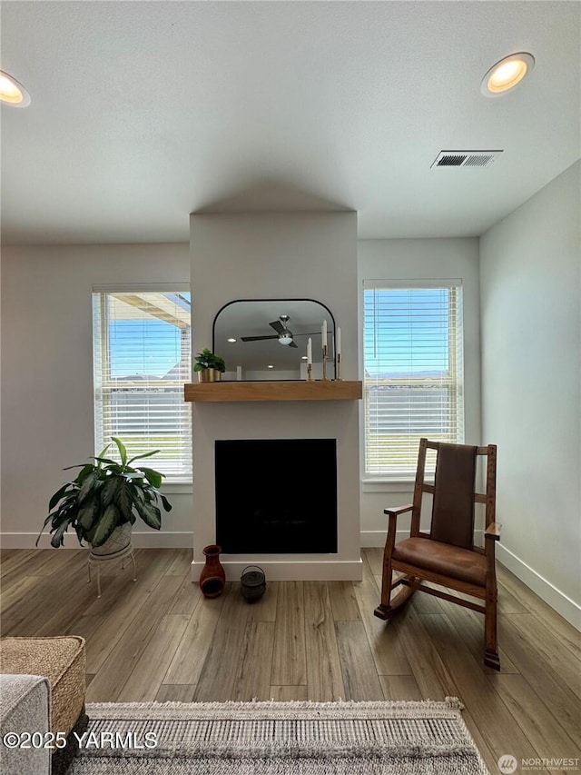 living area featuring a wealth of natural light, visible vents, and wood finished floors