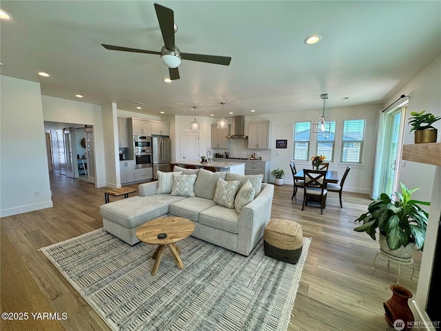 living area featuring light wood-type flooring, ceiling fan, baseboards, and recessed lighting