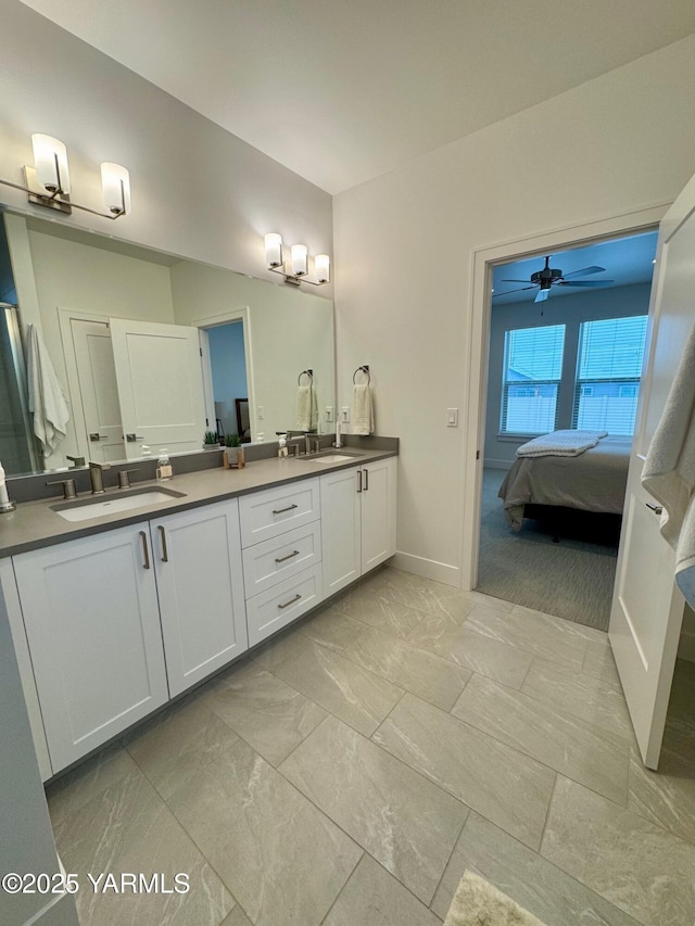 bathroom featuring double vanity, a ceiling fan, a sink, ensuite bath, and baseboards