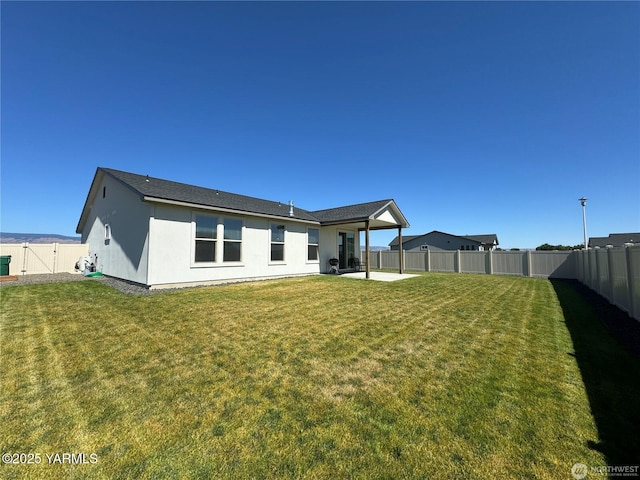 back of house featuring a fenced backyard, a yard, and a patio