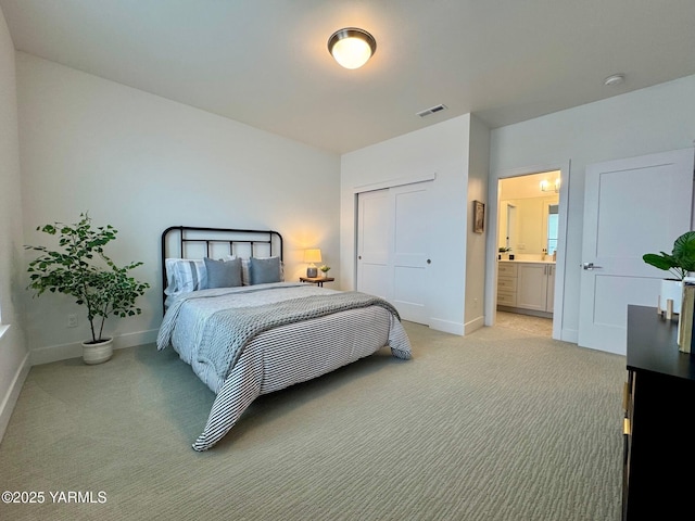 bedroom featuring ensuite bathroom, light colored carpet, visible vents, baseboards, and a closet