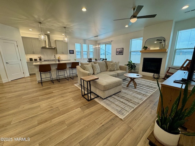 living room with a healthy amount of sunlight, visible vents, a large fireplace, and light wood-style flooring