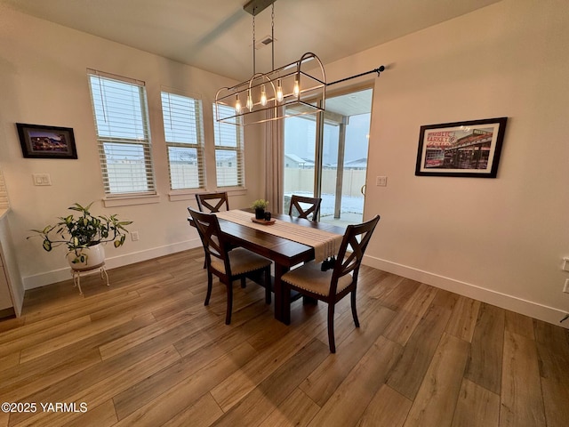 dining room with a notable chandelier, baseboards, and wood finished floors