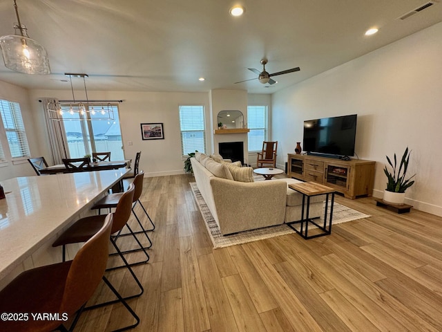 living room featuring light wood finished floors, baseboards, a fireplace, and visible vents