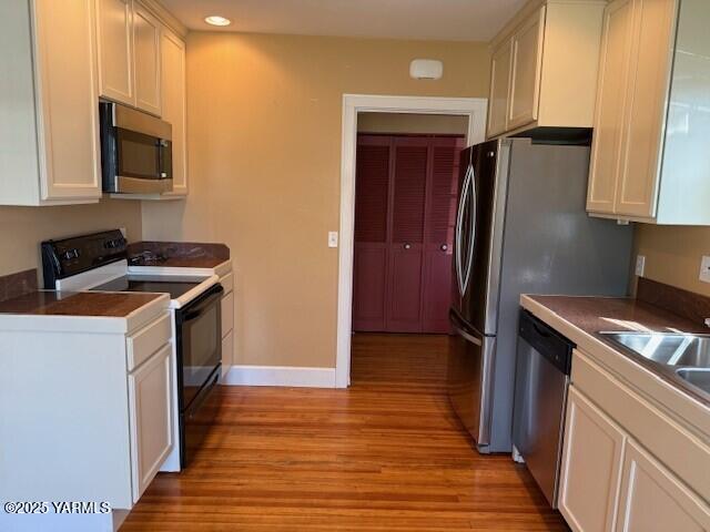 9 W Court St, Union Gap, WA 98903 - kitchen featuring appliances with stainless steel finishes, light wood finished floors, white cabinets, dark countertops, and recessed lighting