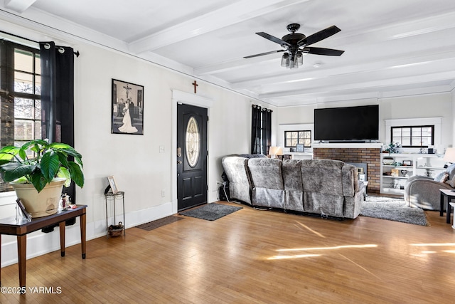 living room featuring beam ceiling, plenty of natural light, and wood finished floors