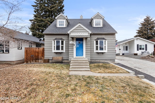 view of front facade featuring entry steps, a front yard, fence, and roof with shingles