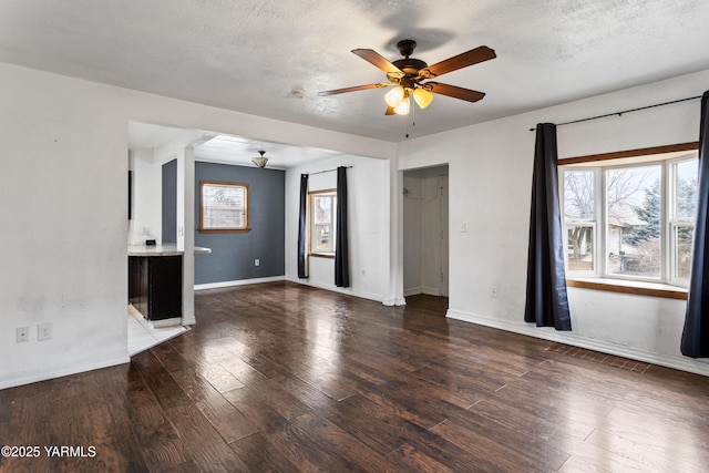 unfurnished living room featuring a ceiling fan, a textured ceiling, baseboards, and dark wood-style flooring