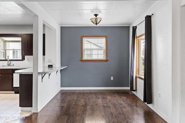 unfurnished dining area featuring baseboards, dark wood finished floors, and a sink