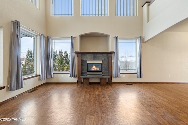 unfurnished living room with visible vents, a fireplace, baseboards, and wood finished floors