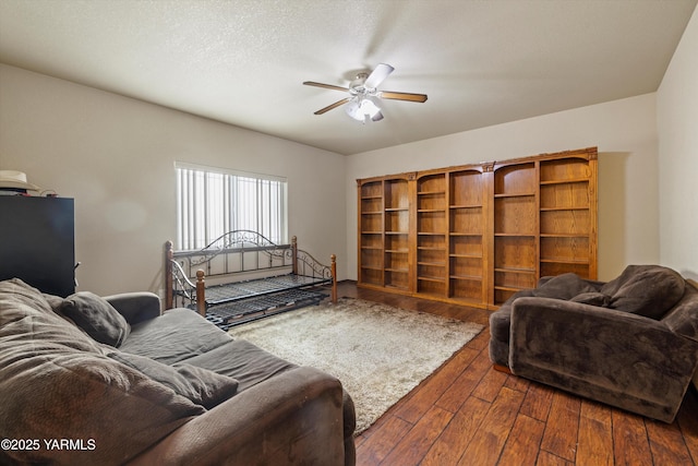 living room with dark wood-style floors, ceiling fan, and a textured ceiling