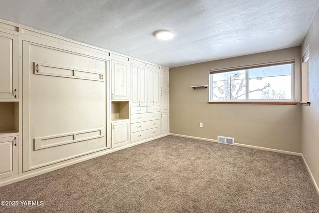 unfurnished bedroom with carpet, visible vents, a textured ceiling, and baseboards