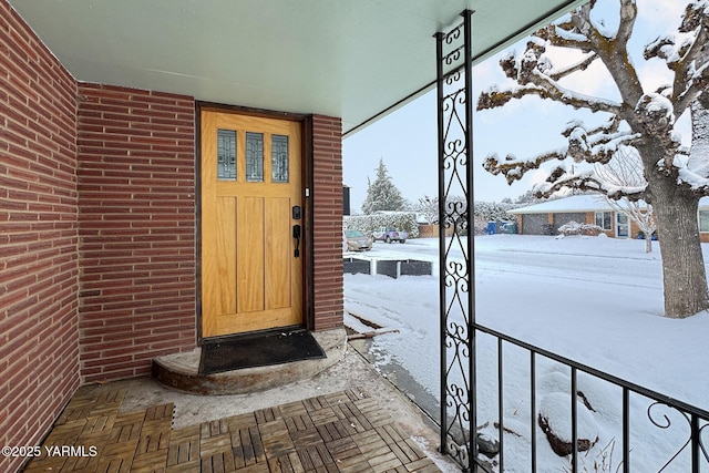 snow covered property entrance with brick siding