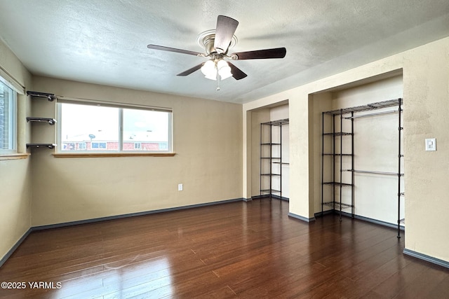 unfurnished bedroom with a textured ceiling, baseboards, and dark wood-style flooring