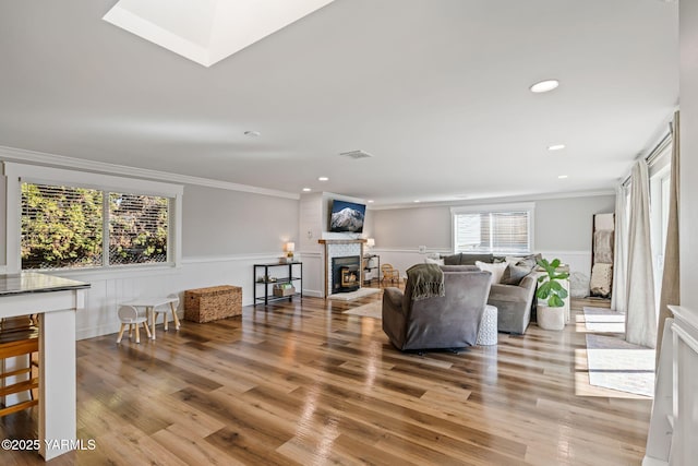 211 N 65th Pl, Yakima, WA 98908 - living room featuring plenty of natural light, wood finished floors, a wainscoted wall, a warm lit fireplace, and ornamental molding